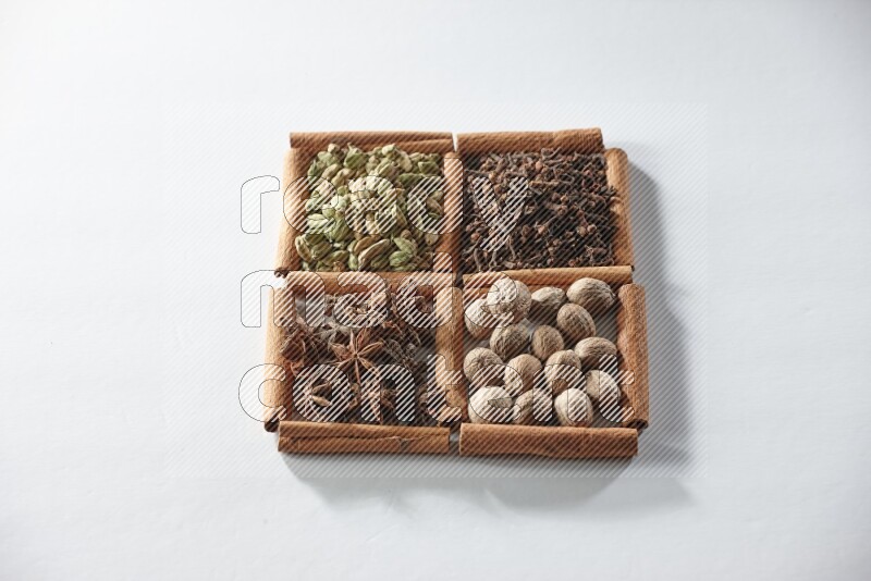 4 squares of cinnamon sticks full of cardamom, star anise, cloves and nutmeg on white flooring