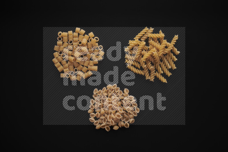 Different pasta types in bunches on black background