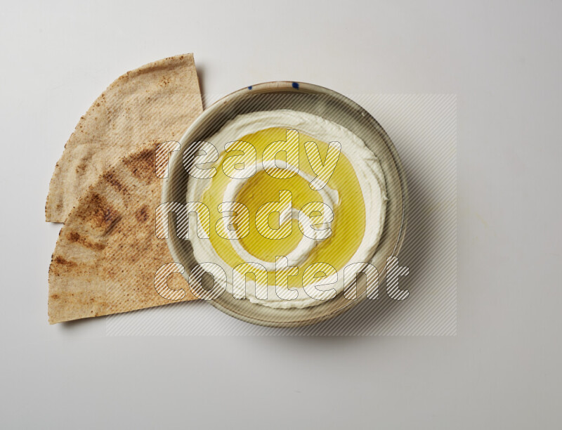 Lebnah garnished with olive oil in a grey pottery plate on a white background