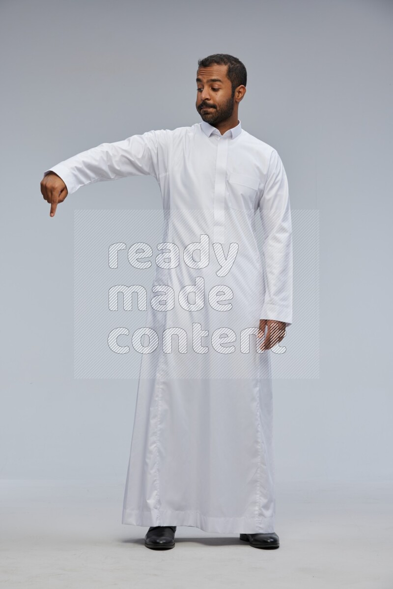 Saudi man Wearing Thob standing interacting with the camera on Gray background