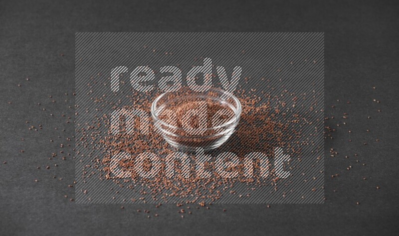 وعاء زجاجي ممتلئ ببذور حب الرشاد محاط بالبذور على أرضية سوداء