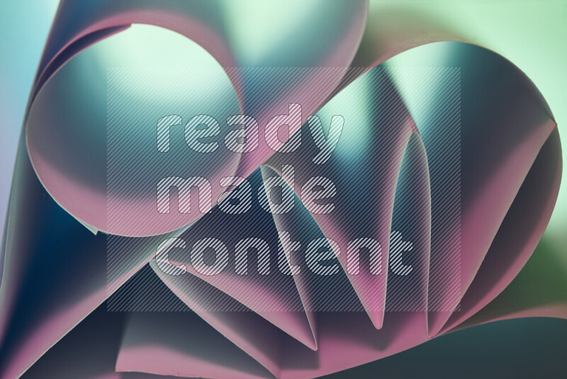 An artistic display of paper folds creating a harmonious blend of geometric shapes, highlighted by soft lighting in green and pink tones