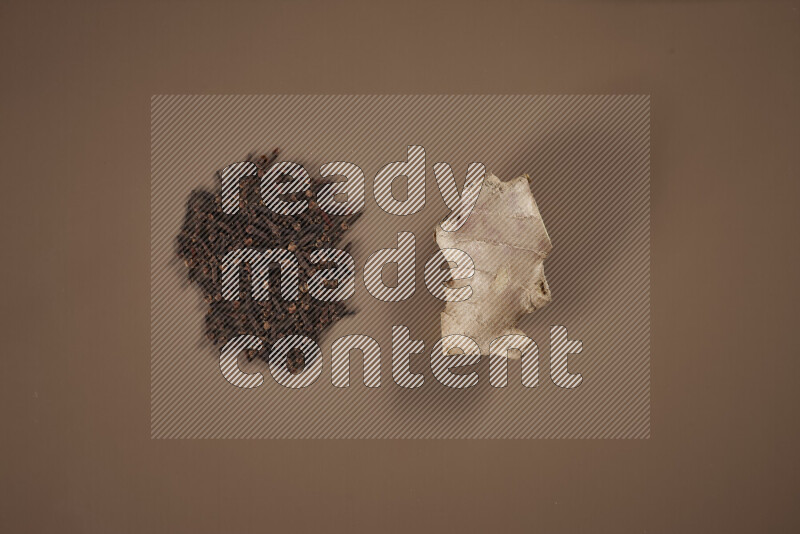 بهارات كاملة متنوعة تتضمن زنجبيل طازج ومجفف، أعواد قرفة، هيل، أصابع كركم، قرنفل، يانسون نجمي على خلفية بيج