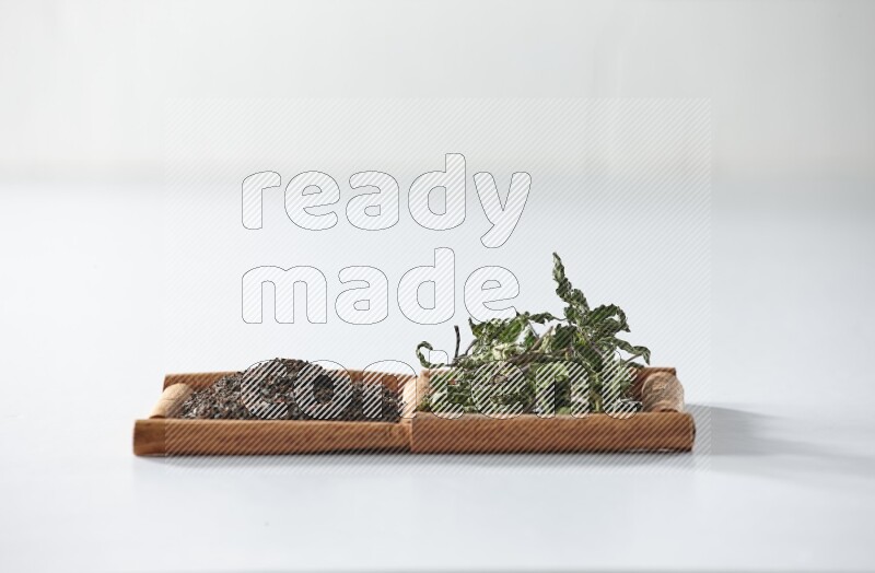 2 squares of cinnamon sticks full of black tea and dried mint leaves on white flooring