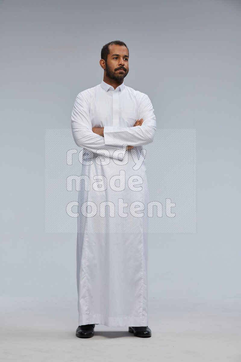 Saudi man wearing Thob standing with crossed arms on Gray background