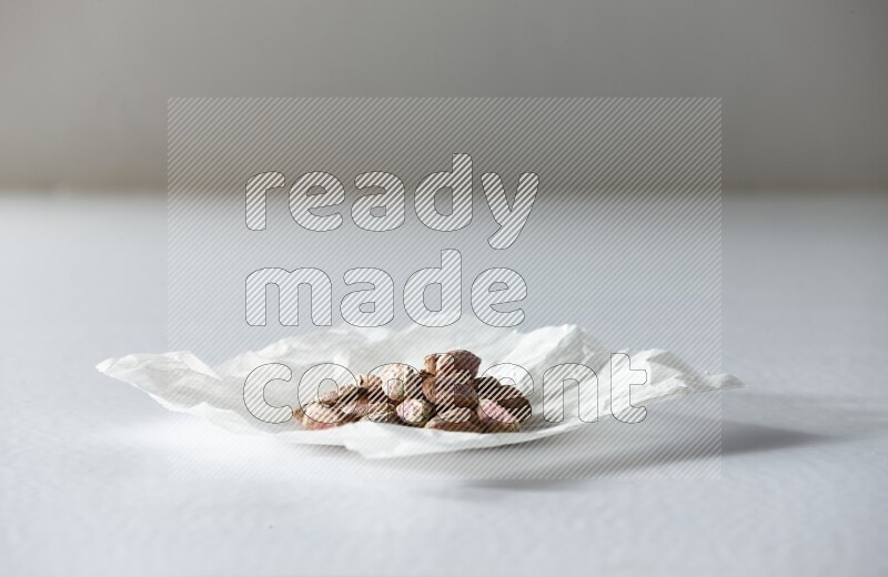Peeled pistachios on a crumpled piece of paper on a white background in different angles