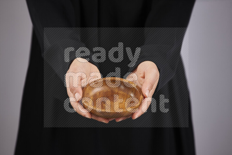A woman in black abaya holding different wooden essentials in different positions