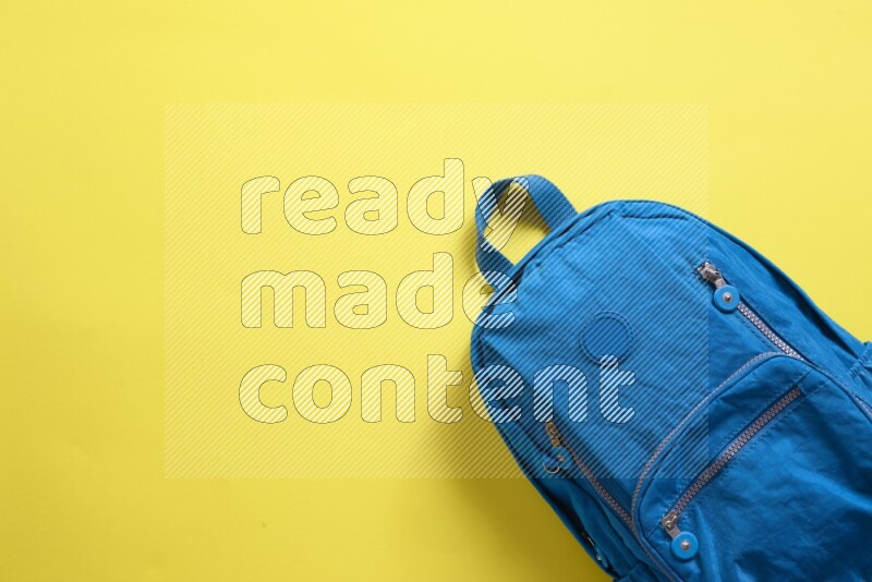 A blue school bag placed on yellow background