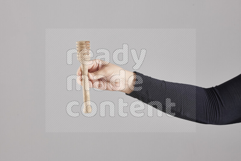 A woman in black abaya holding different wooden essentials in different positions