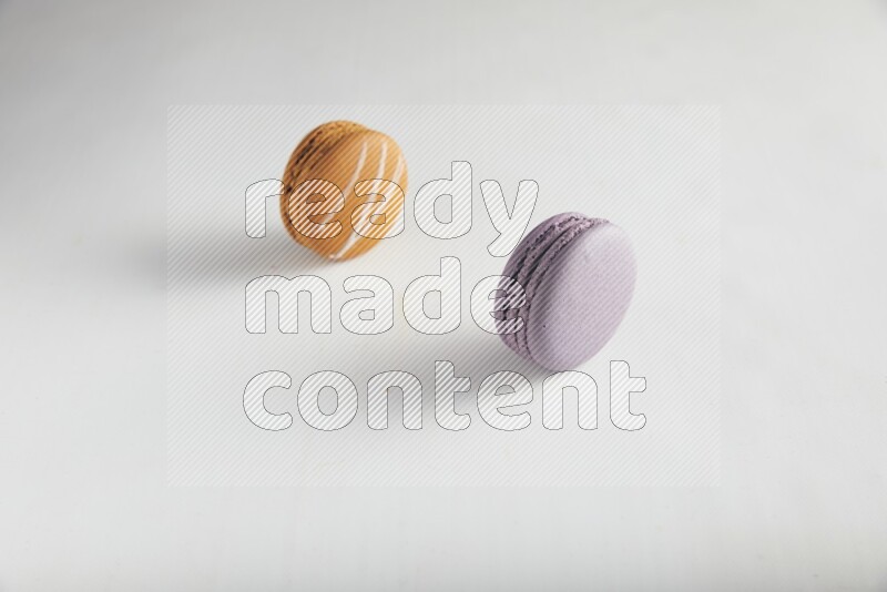 45º Shot of of two assorted Brown Irish Cream, and Purple Blueberry macarons on white background