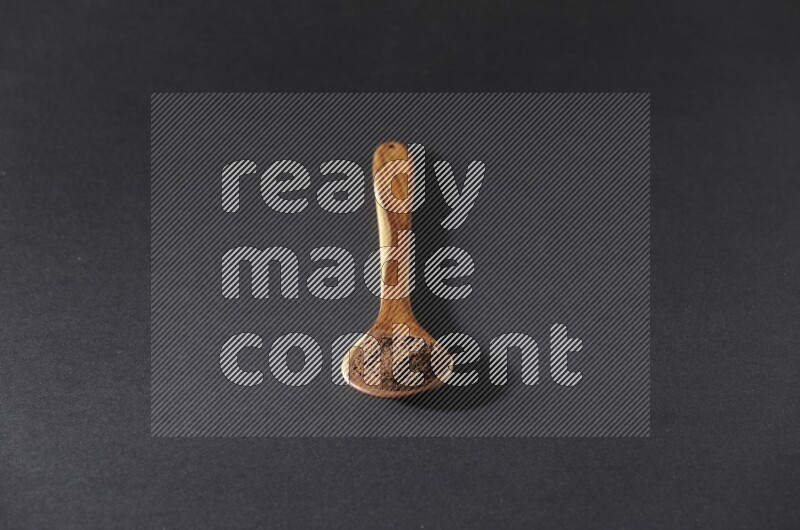 بودرة القرنفل في ملعقة خشبية علي خلفية سوداء