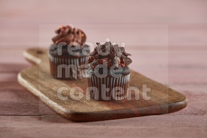 Chocolate mini cupcake topped with chocolate curls on a wooden board