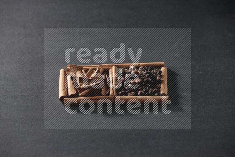 مربعان من أعواد القرفة ممتلئان بحبوب القهوة وقطع من القرفة علي خلفية سوداء