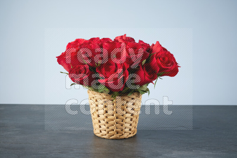 Vibrant red roses in a wicker basket on black marble background