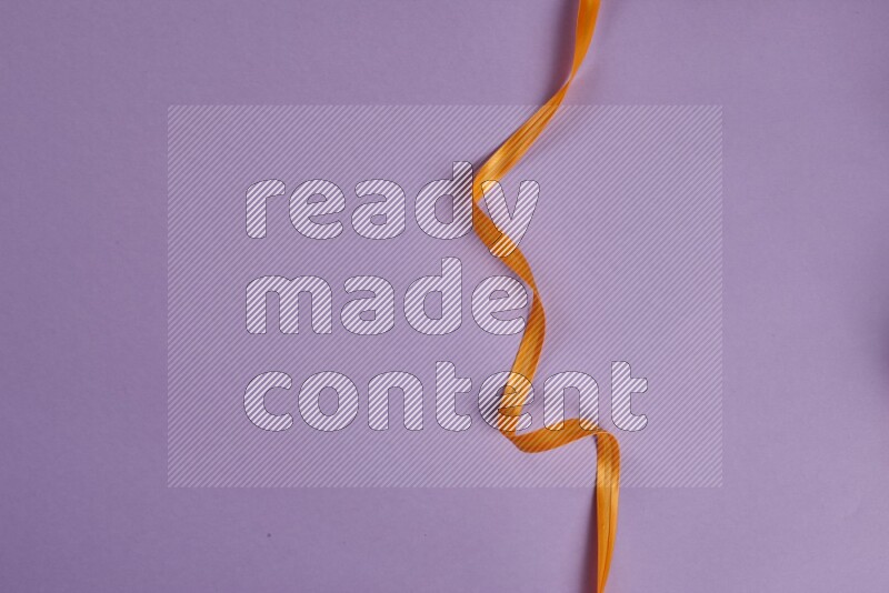 An orange collection of sewing and tailoring tools arranged on a purple background