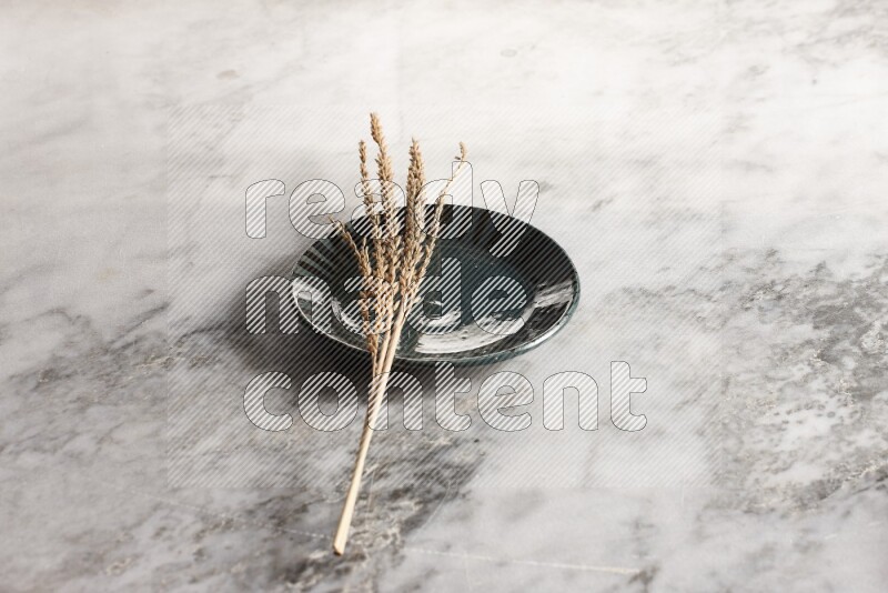 Wheat stalks on multicolored pottery plate on grey marble background