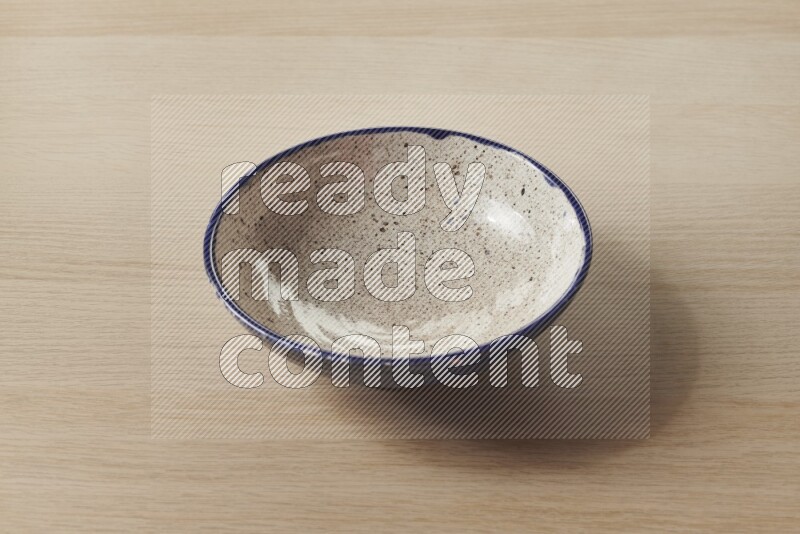 A multicolored pottery bowl on light wooden background