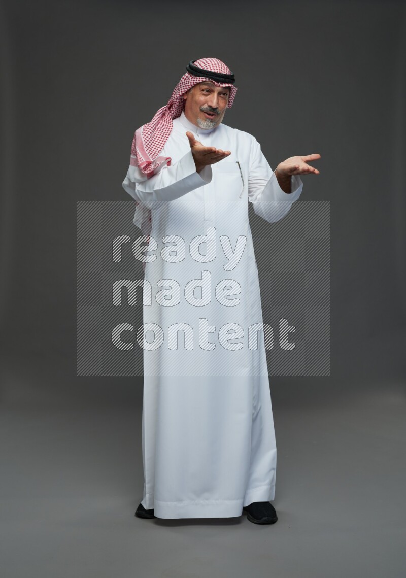 Saudi man with shomag Standing Interacting with the camera on gray background