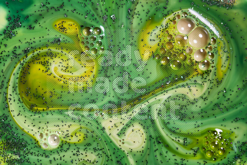 A close-up of sparkling green glitter scattered on swirling yellow and green background