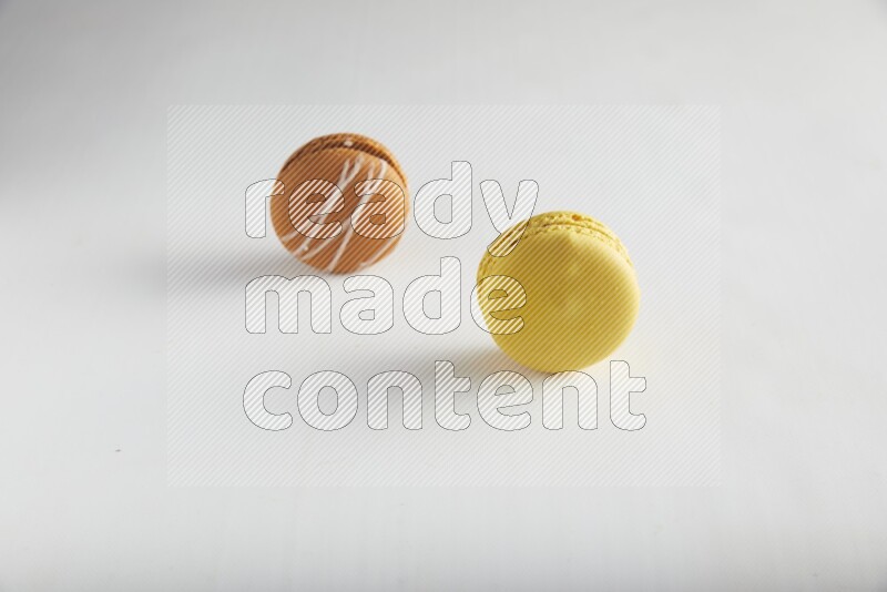 45º Shot of of two assorted Brown Irish Cream, and Yellow Lemon macarons on white background