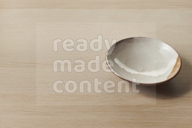 A multicolored pottery plate on light wooden background