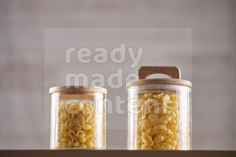 Raw pasta in glass jars on beige background