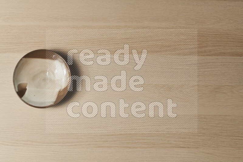 A multicolored pottery plate on light wooden background