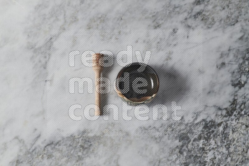 Multicolored pottery bowl with wooden honey dipper on the side on grey marble background