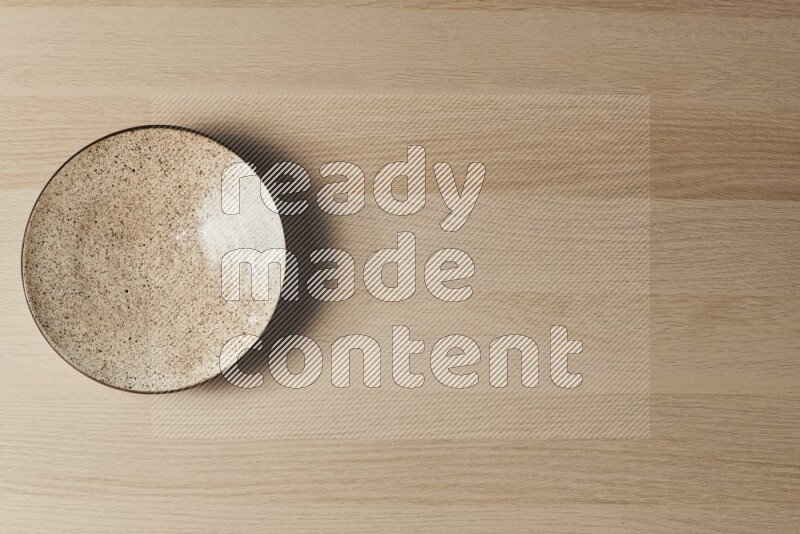 A multicolored pottery plate on light wooden background