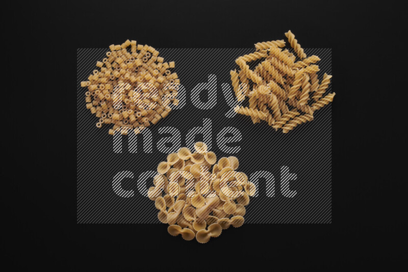 Different pasta types in bunches on black background