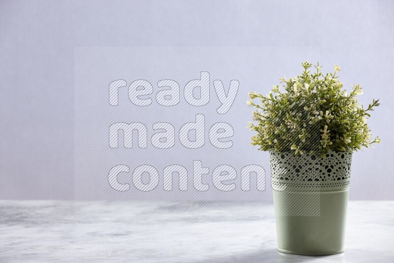 Artificial plant in green decorative pot on grey marble background