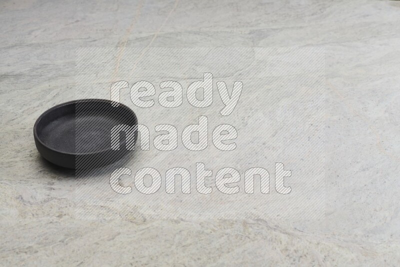 A black pottery oven bowl on grey marble background