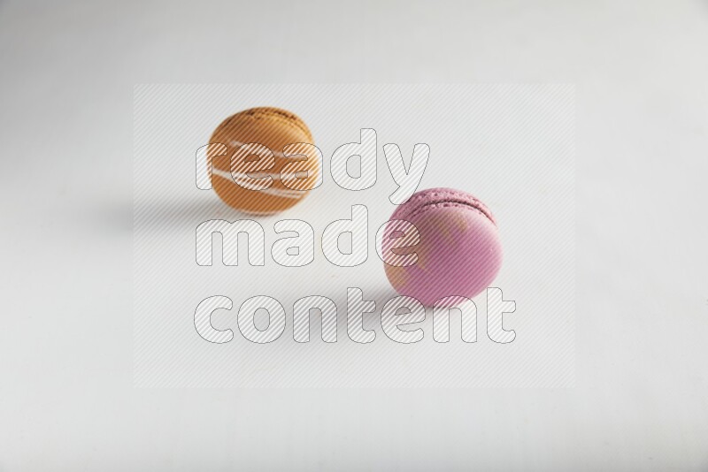 45º Shot of of two assorted Brown Irish Cream, and Purple Strawberry macarons on white background