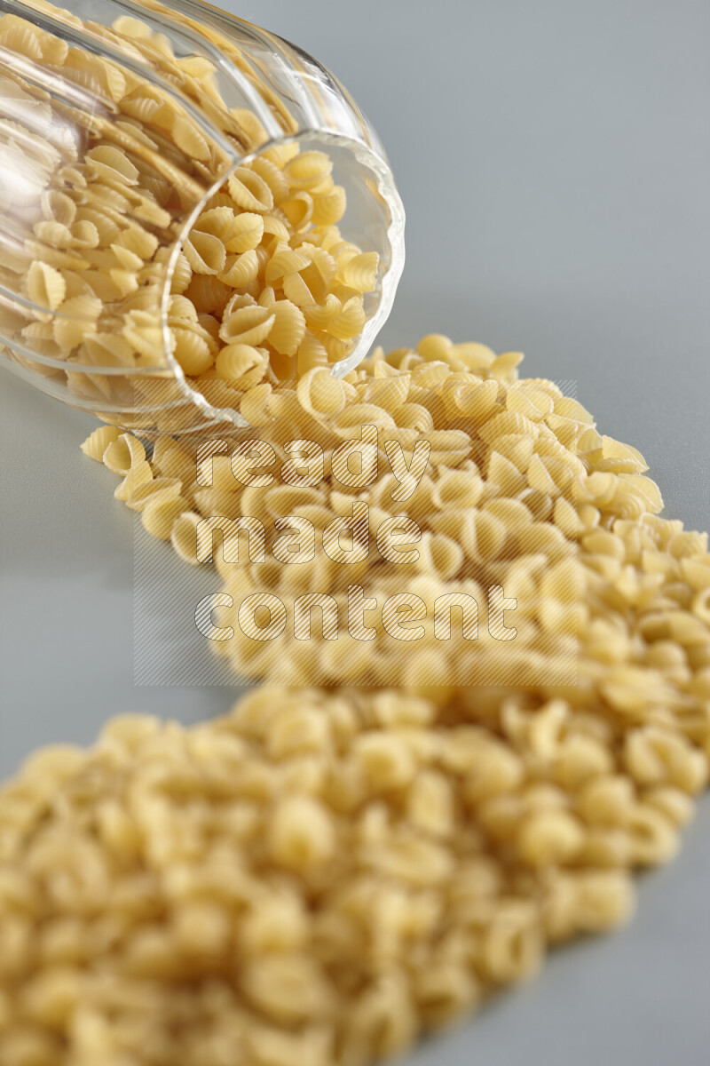 Flipped jar full of raw pasta on light blue background