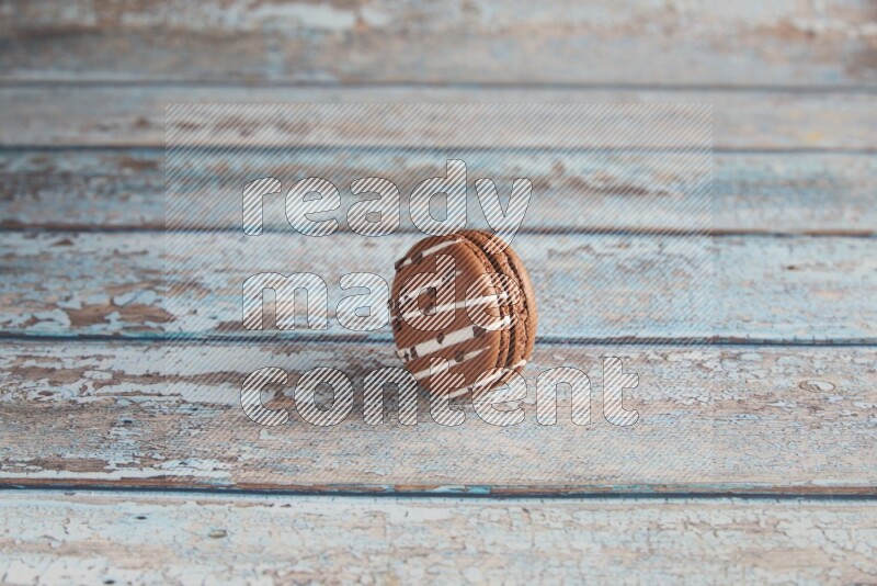 45º Shot of Brown white Chocolate Caramel macaron on light blue wooden background