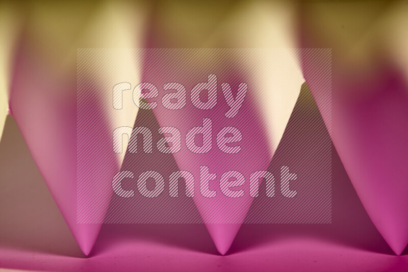 A close-up abstract image showing sharp geometric paper folds in pink gradients and warm tones