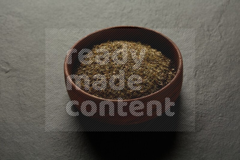 wooden round sauce bowl filled with herbs on grey textured countertop