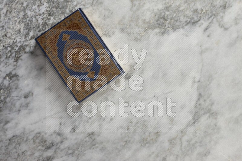 Quran with a prayer beads on grey marble background