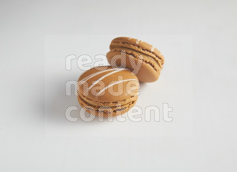 45º Shot of two Brown Irish Cream macarons on white background