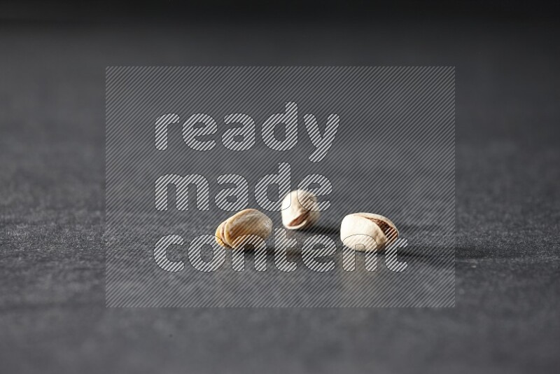 3 pistachios on a black background in different angles