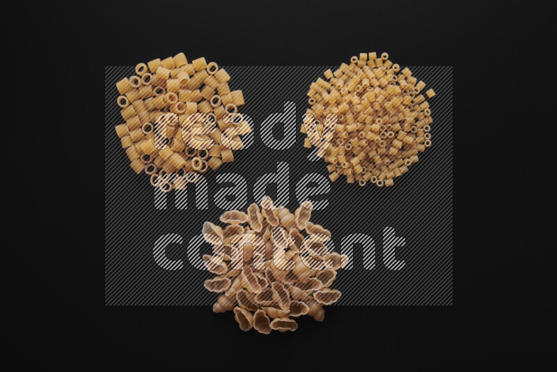 Different pasta types in bunches on black background