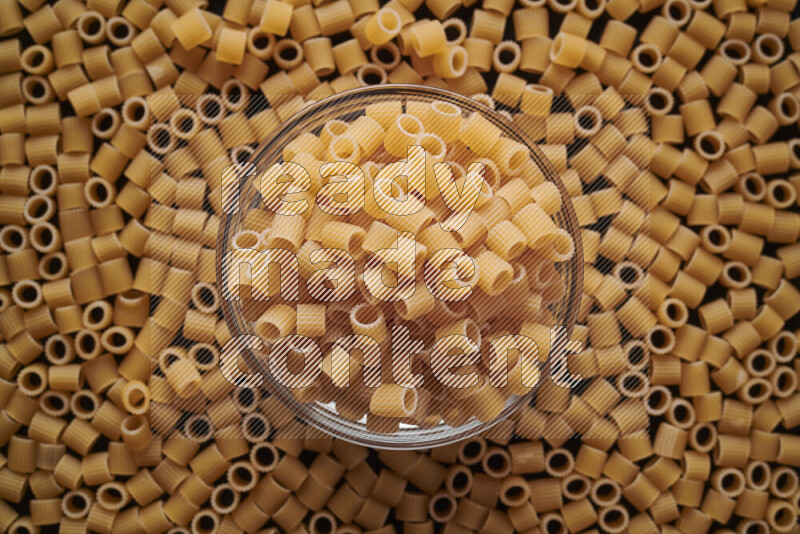 Big rings pasta in a glass bowl on black background