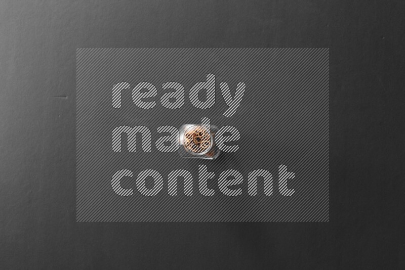 A glass spice jar full of cinnamon sticks on black flooring