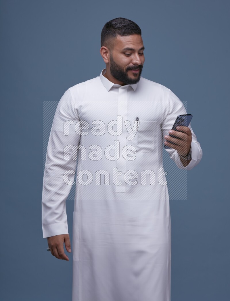 A man Texting on Blue Background wearing Saudi Thob