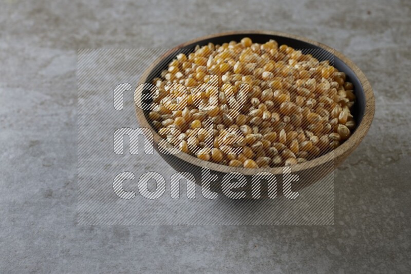 corn kernel in a wooden bowl on a grey textured countertop