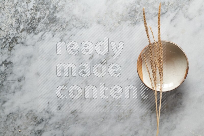 Wheat stalks on multicolored pottery plate on grey marble background