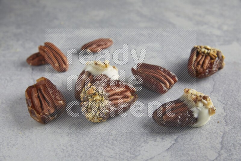 group of pecan stuffed dates plain and covered with dark and white chocolate  on alight grey background