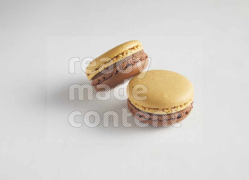 45º Shot of two Yellow and Brown Chai Latte macarons on white background