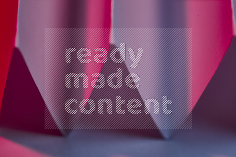 A close-up abstract image showing sharp geometric paper folds in blue and red gradients