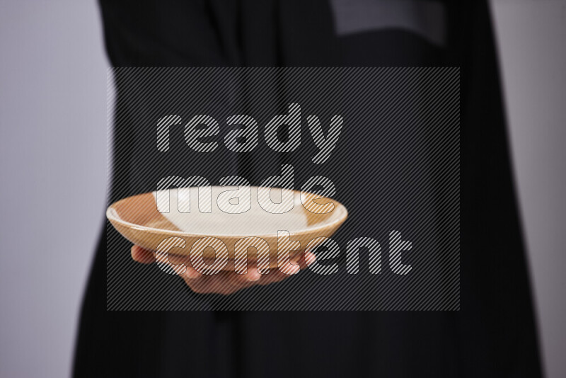 A woman in black abaya holding different pottery essentials in different positions